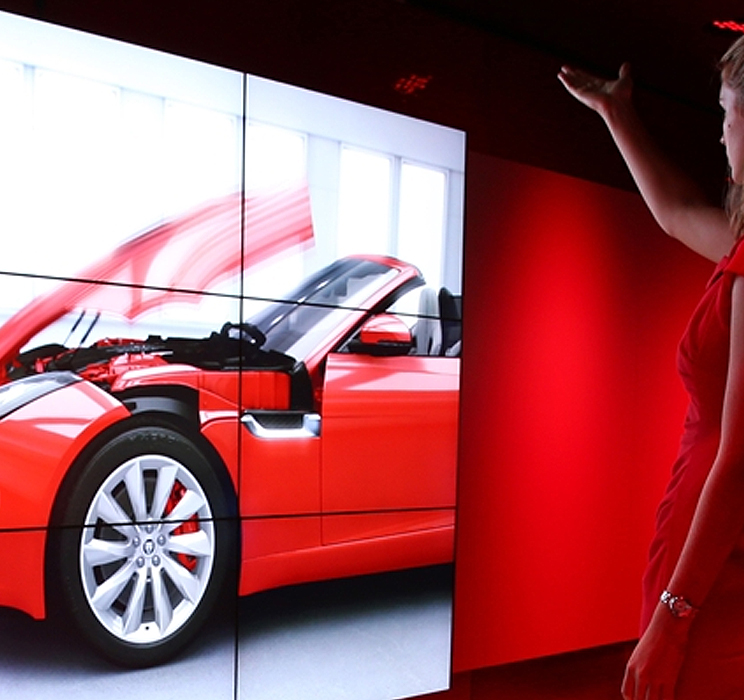 The end result of this initiative - a 5.5ft by 12ft wide screen with a lady gesturing to control a high-resolution 3D graphic of the yet-to-be launched F-Type Jaguar or L405 Landrover